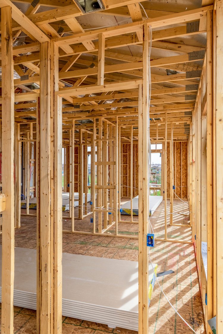 Interior framework of a house under construction with exposed wooden studs and beams.